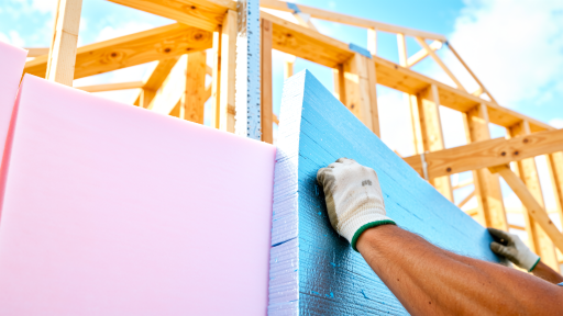 Professional applying spray polyurethane foam with proper technique and safety equipment, construction site